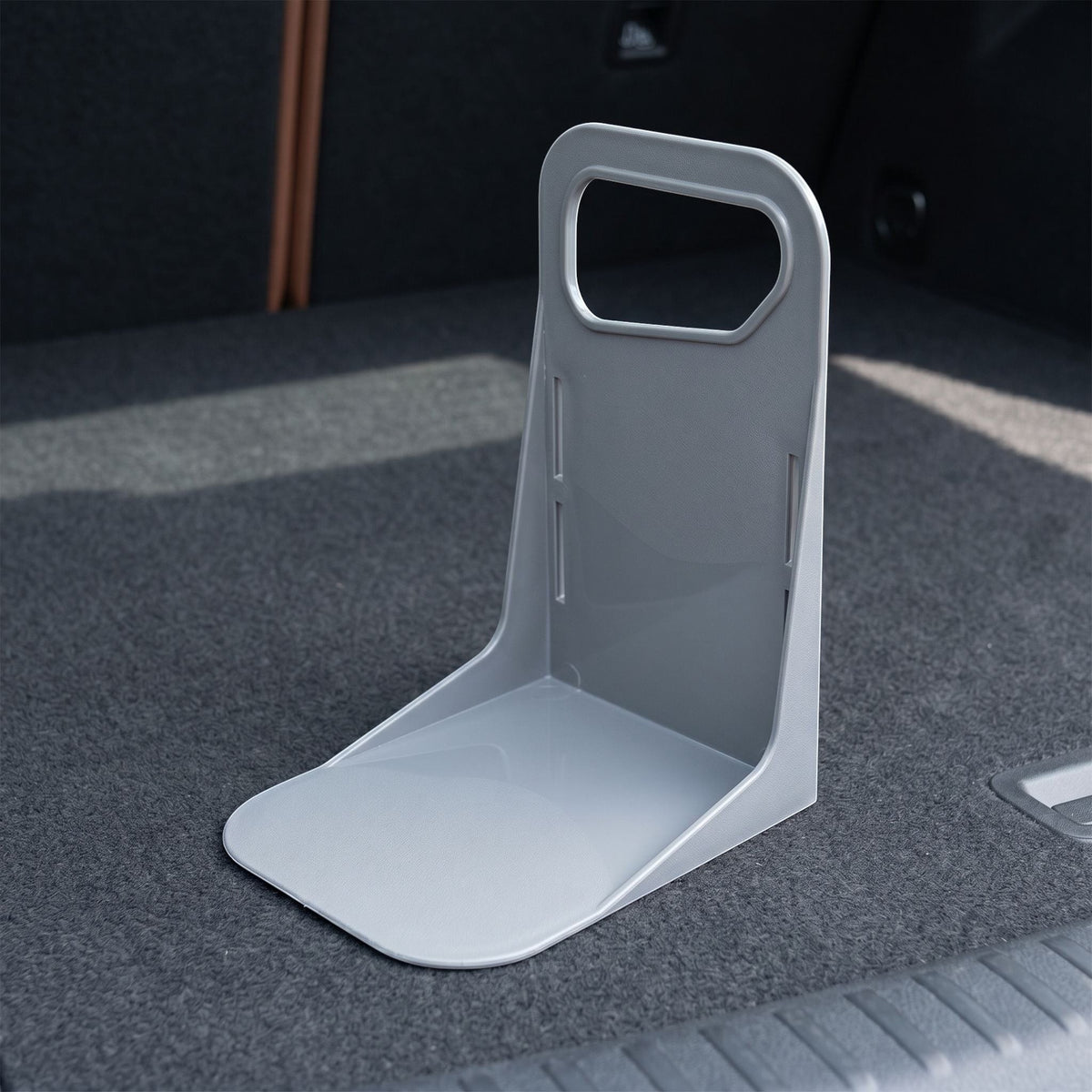 Close-up of a small plastic trunk organizer demonstrating durable material and anti-slip bottom in a garage setting.