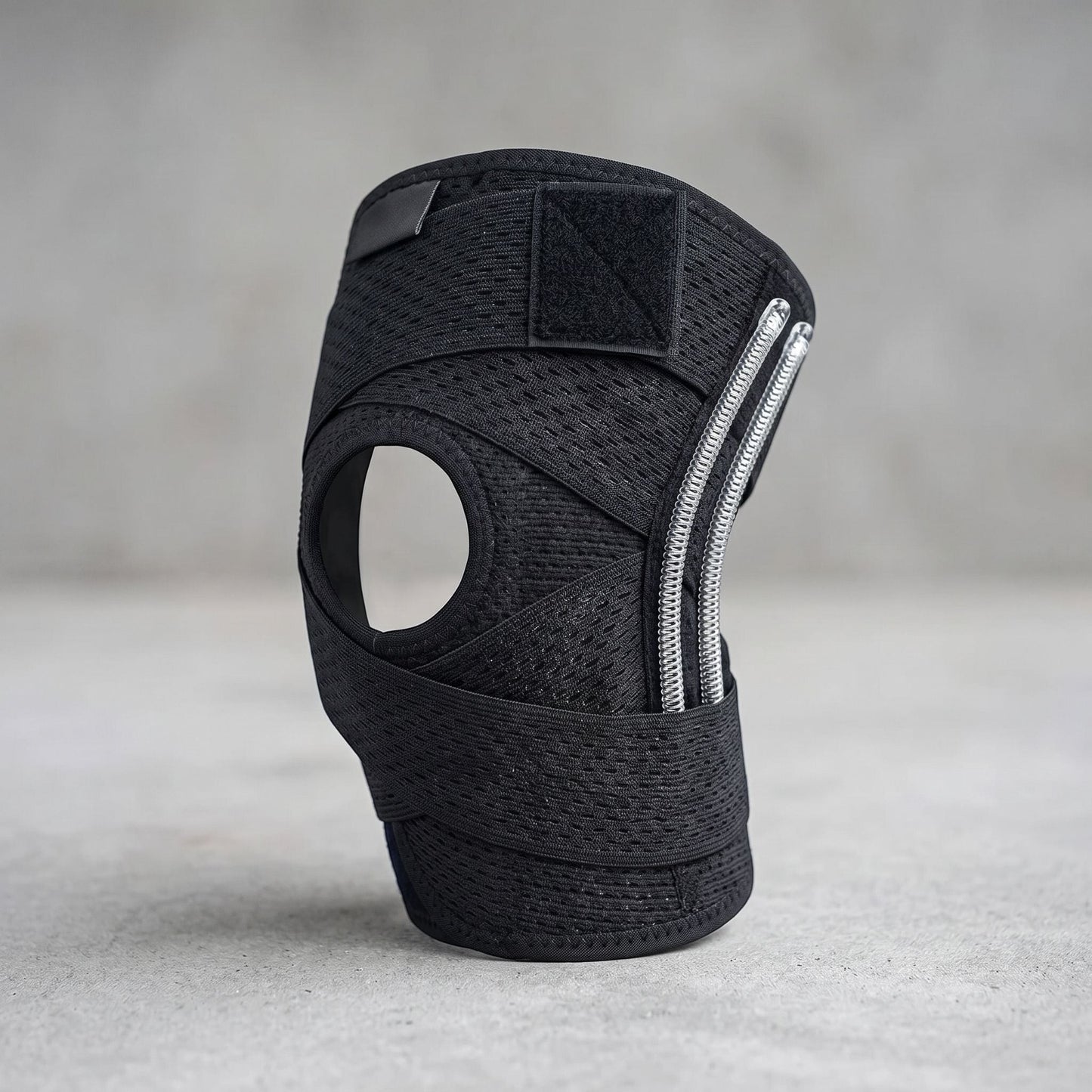 Unbranded compression knee brace with side stabilizers, adjustable straps, and breathable knit fabric, shown in a studio setting.