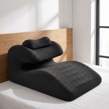 Curved lumbar support pillow supporting bed setup against a wooden headboard in natural daylight.