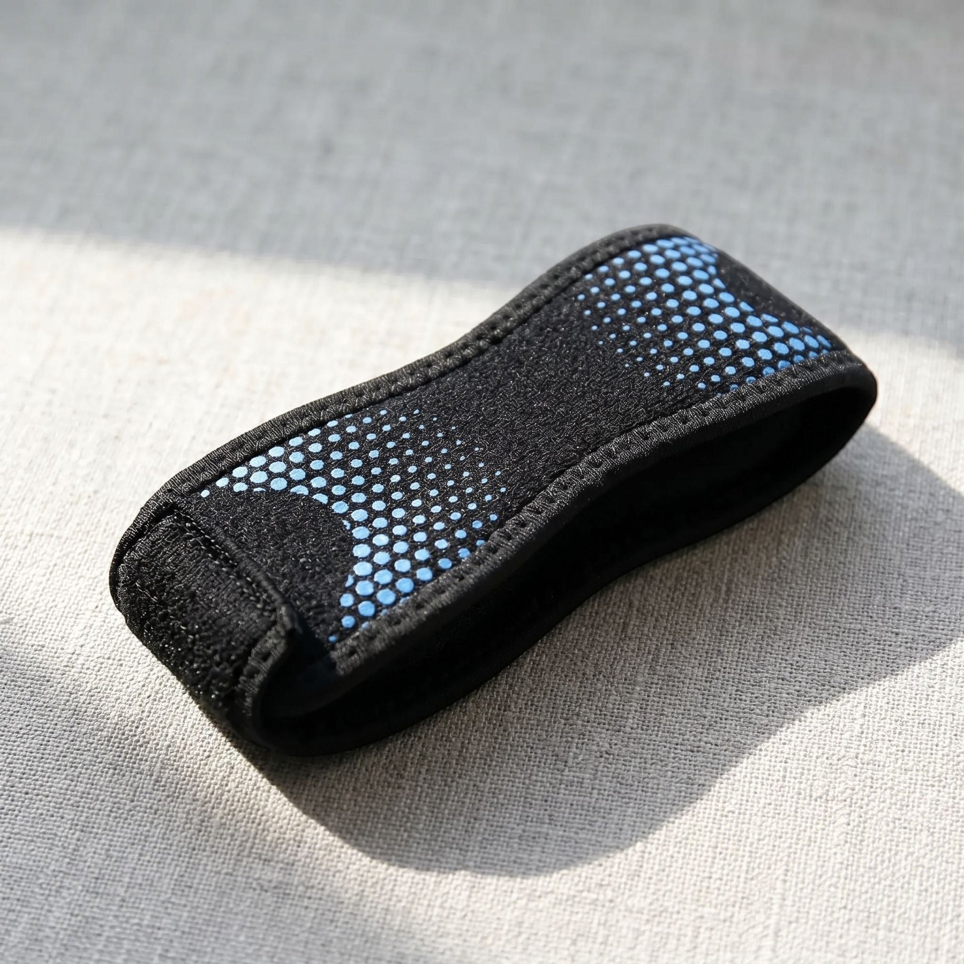 Close-up of knee strap placed on textured surface highlighting adjustable strap and knit fabric details.