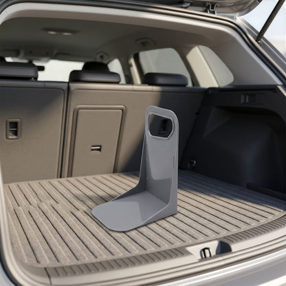 Lifestyle scene showing a small plastic trunk organizer at an angle in a car trunk with soft sunlight highlighting its shape and material.