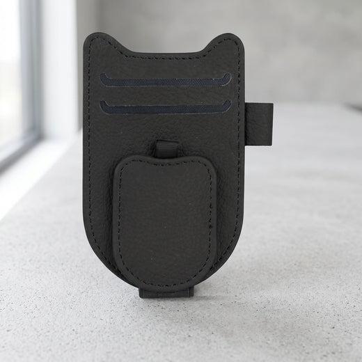 Clean product photo of magnetic car sunglasses holder clip with leatherette finish, centered on neutral surface in well-lit studio.