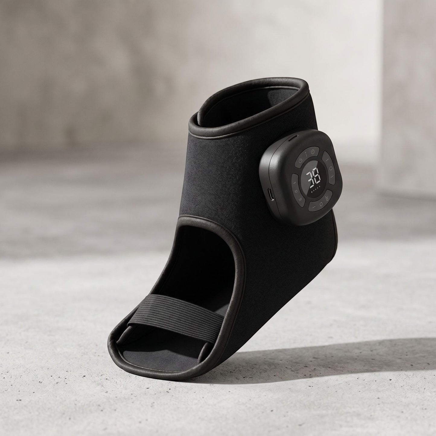 Modern black cordless foot and ankle massager with fabric wrap on bathroom countertop, natural light highlights surface and details.