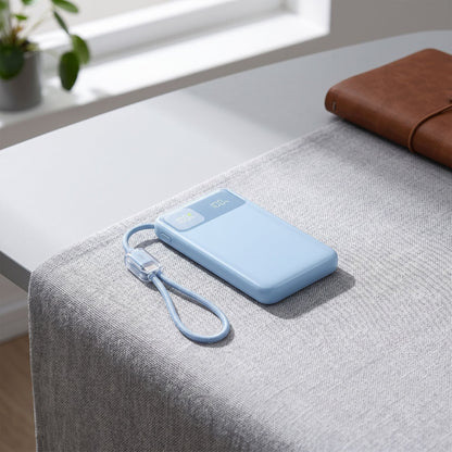 Modern workspace scene with a small power bank displaying battery status and dual USB-C cables on a textured surface.