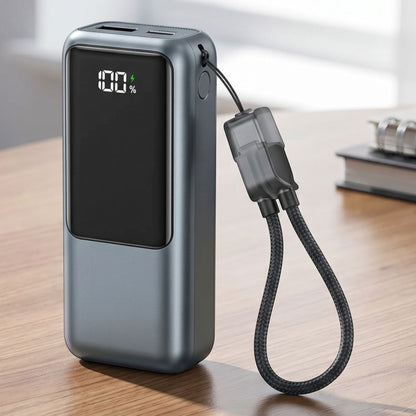 Compact power bank with digital display and built-in USB-C cable placed on a wooden table in natural daylight, showcasing portability.