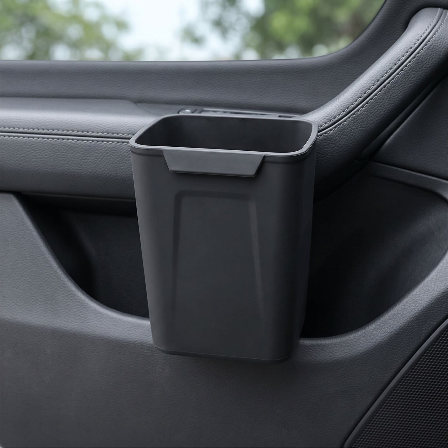 Unbranded silicone car trash bin clipped onto a vehicle door panel, showcasing its compact design and waterproof silicone surface in a realistic car interior setting.