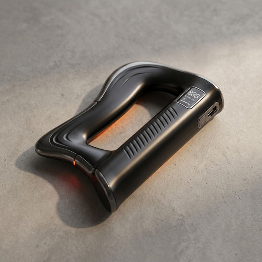 Top-down perspective of a small fascia massage blade on neutral surface, showing edges, ports, and heating feature.