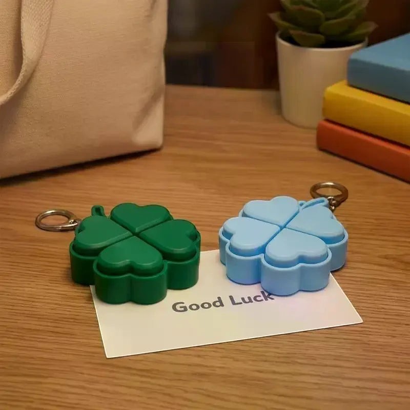 zero2cart green and blue four-leaf clover light-up pop-it fidget keychains on a wooden desk with a Good Luck card