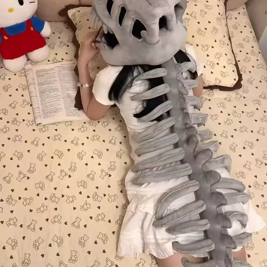 zero2cart grey plush dinosaur skeleton costume set worn by a person lying on a bed with a book