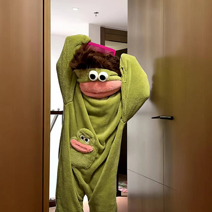 zero2cart green monster fleece onesie pajamas with a pink mouth and large eyes, worn by a person brushing their hair