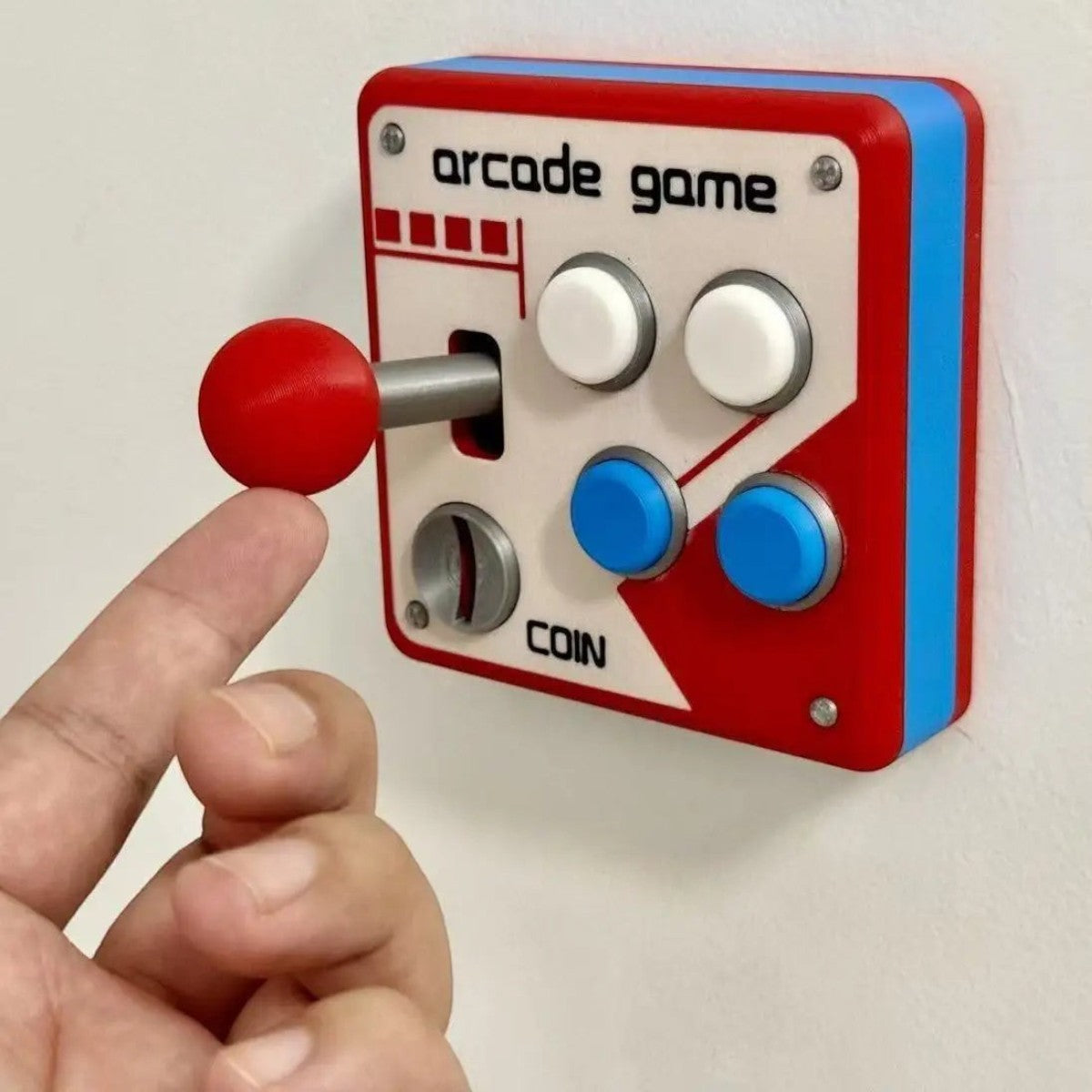 zero2cart retro arcade light switch cover with red joystick and colorful buttons mounted on a white wall