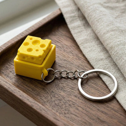 zero2cart yellow cheese-shaped fidget clicker keychain on a wooden tray with a linen cloth
