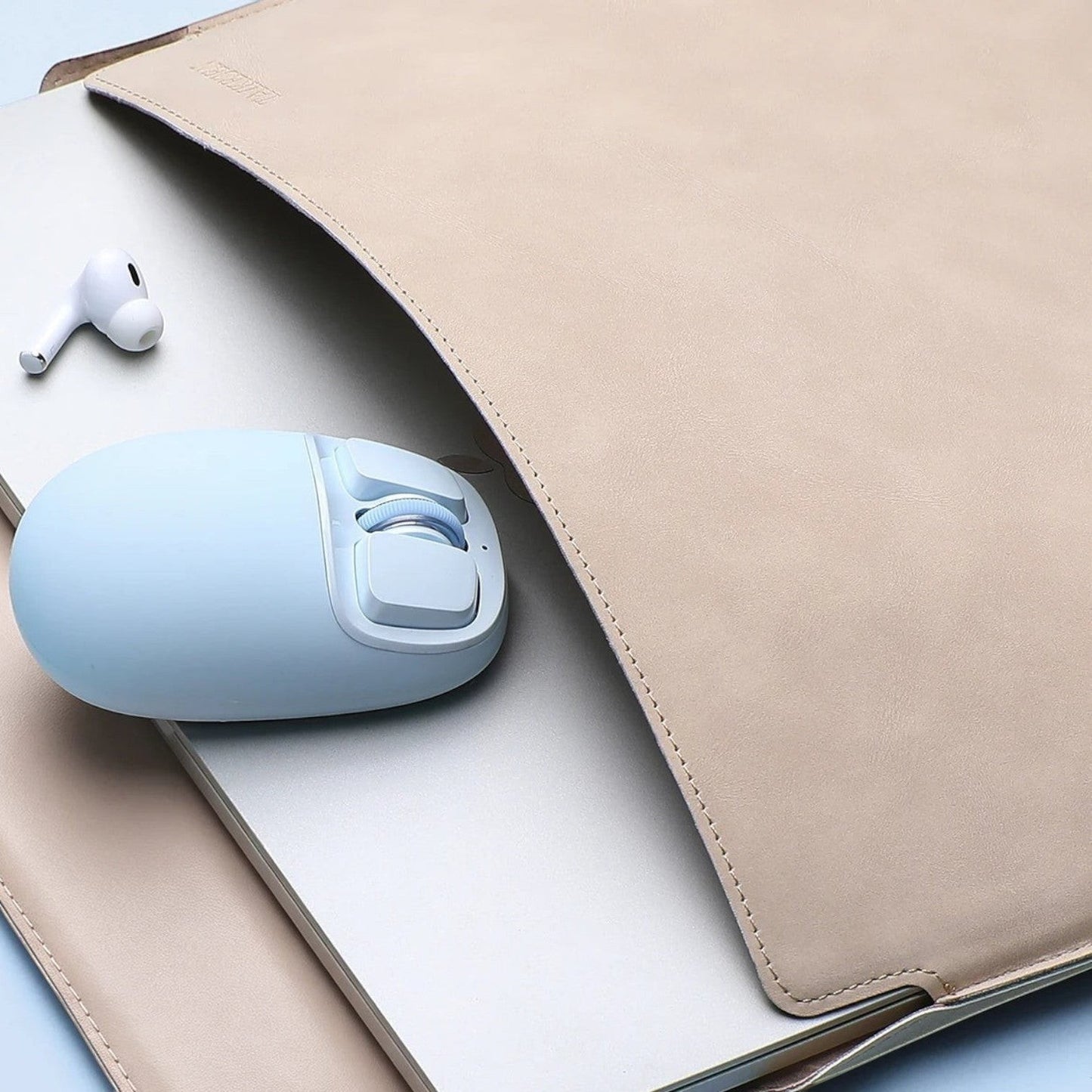 zero2cart YUNZII C1 light blue silicone wireless mouse resting on a laptop inside a beige leather sleeve